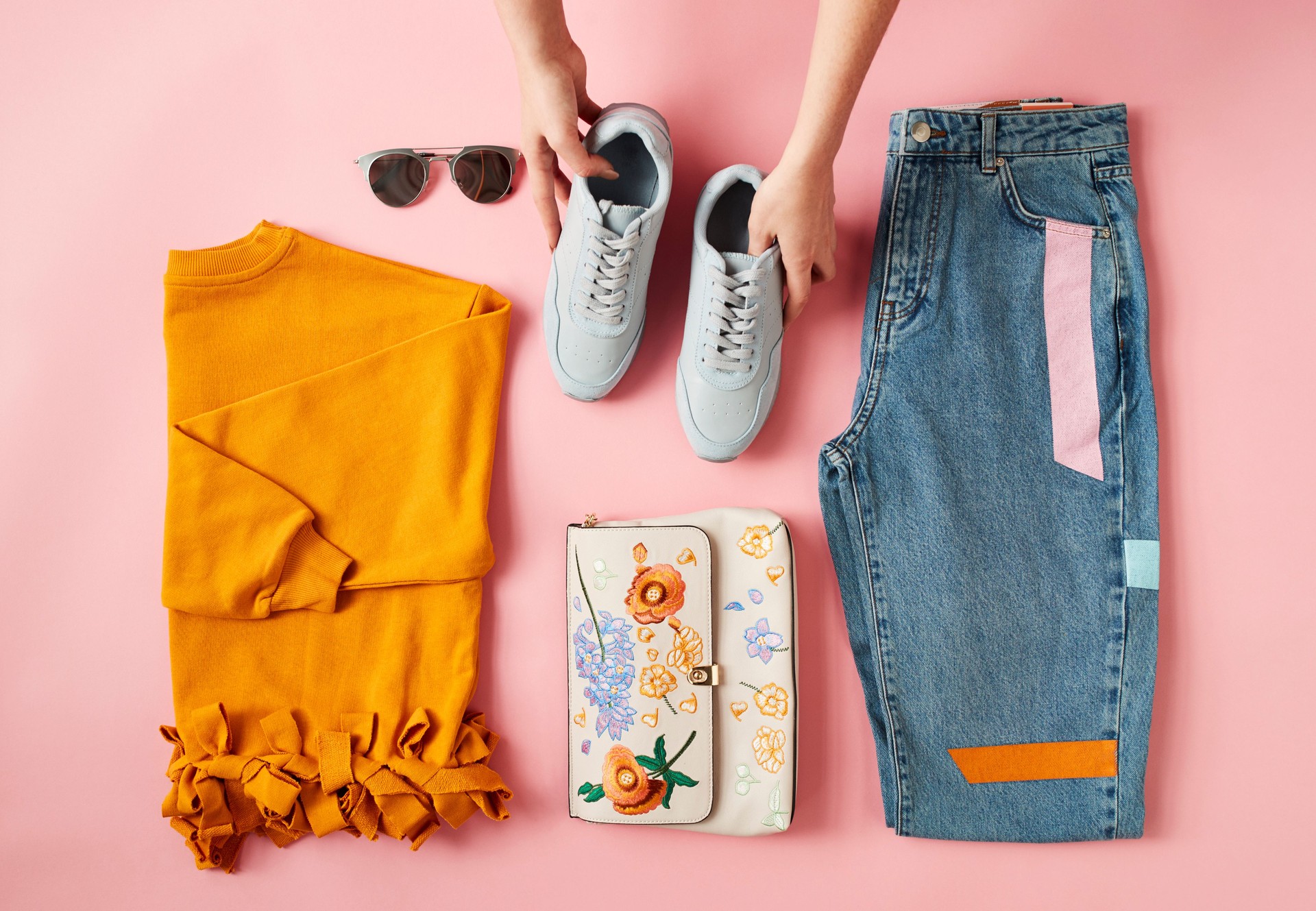 Hands Arranging Flat Lay Shot Of Female Autumn Clothing